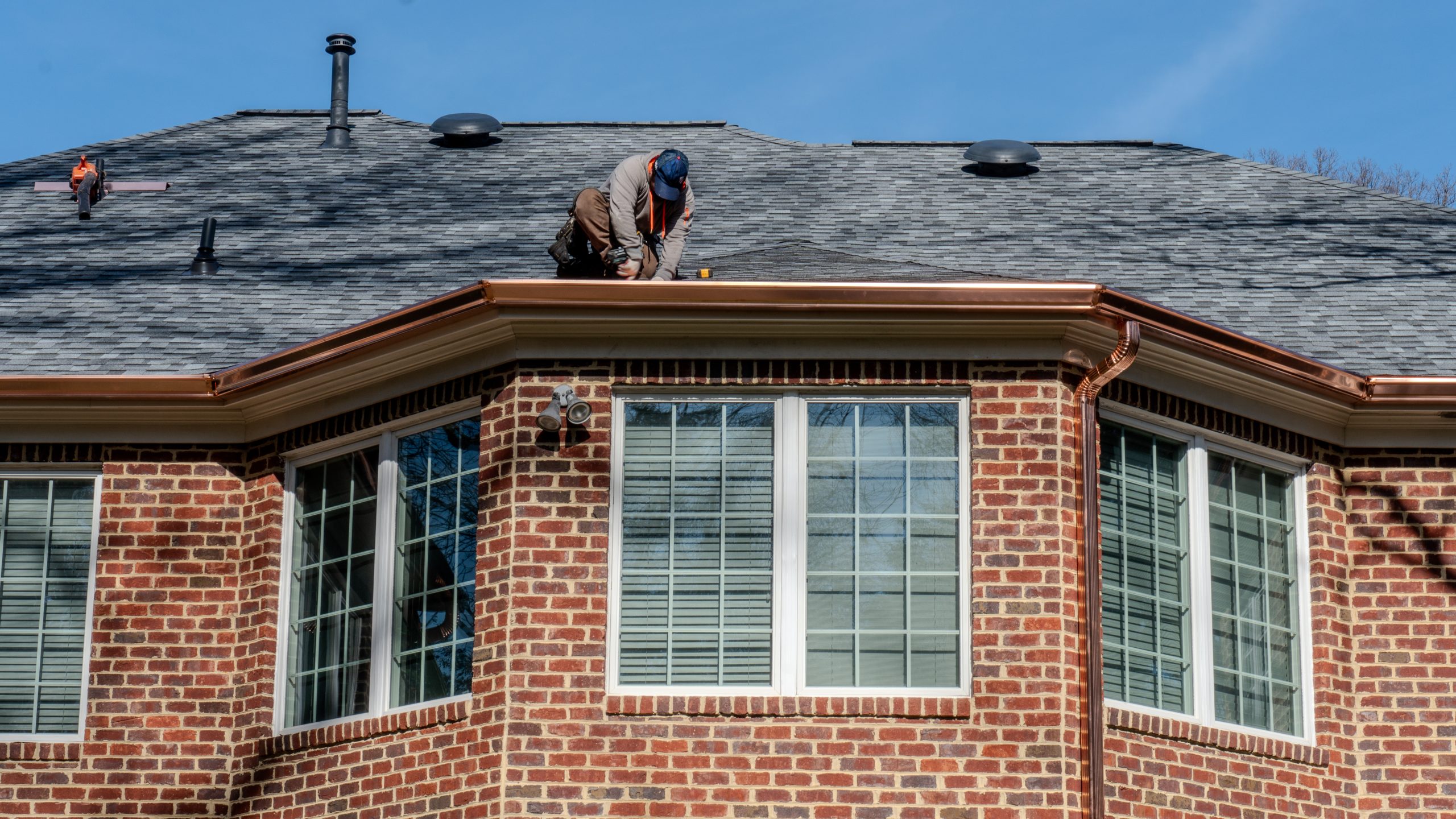Impact Roofing & Renovations installing new copper gutter system on residential home.