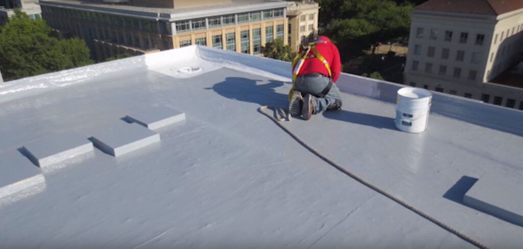 Worker installing modified bitumen roof on a building